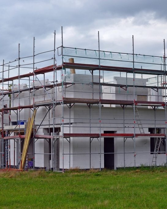 Woning in aanbouw met steigers rondom de ruwbouw van kalkzandsteen